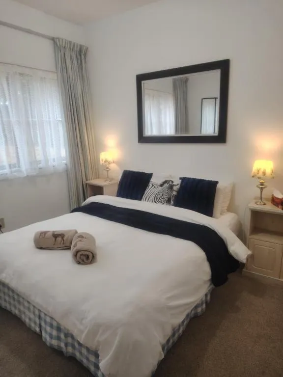 Double bedroom with bedside lamps, a dark blue throw and sheer curtains