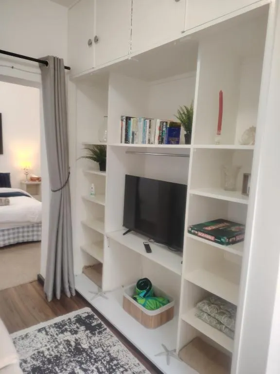 Built-in unit with open shelving, books and a wall-mounted TV beside the bedroom