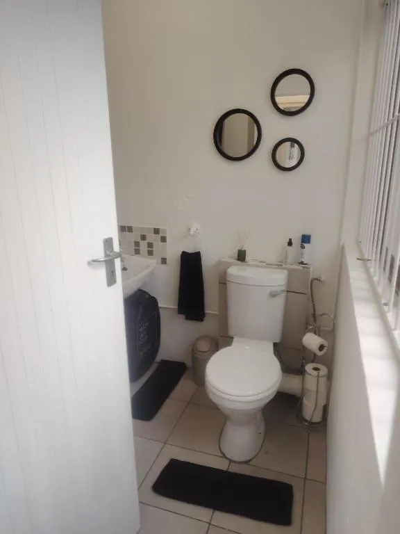 Guest toilet with round mirrors, tiled floor and a narrow window