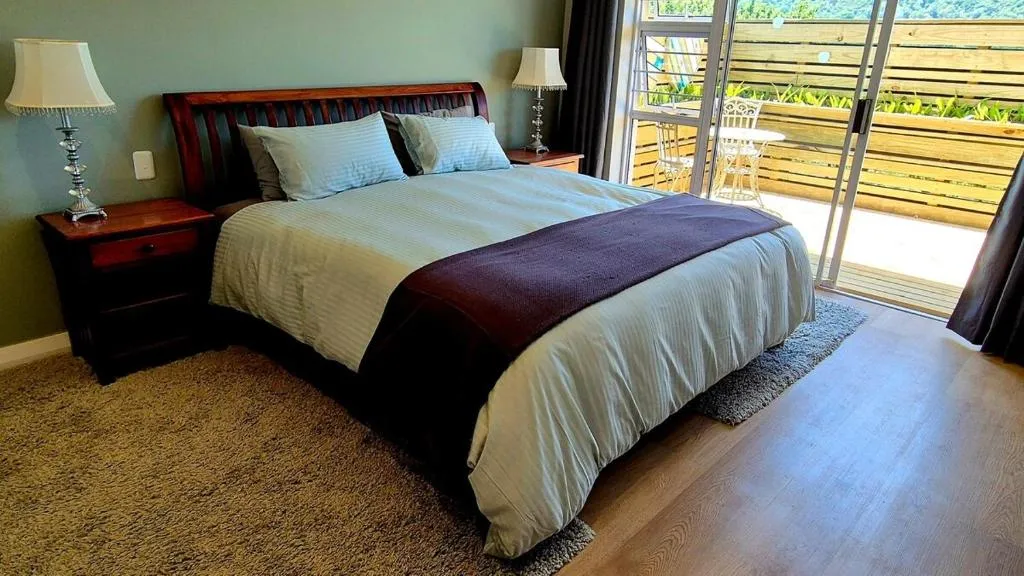 Bedroom with a dark wood sleigh bed and French doors opening onto a wooden balcony