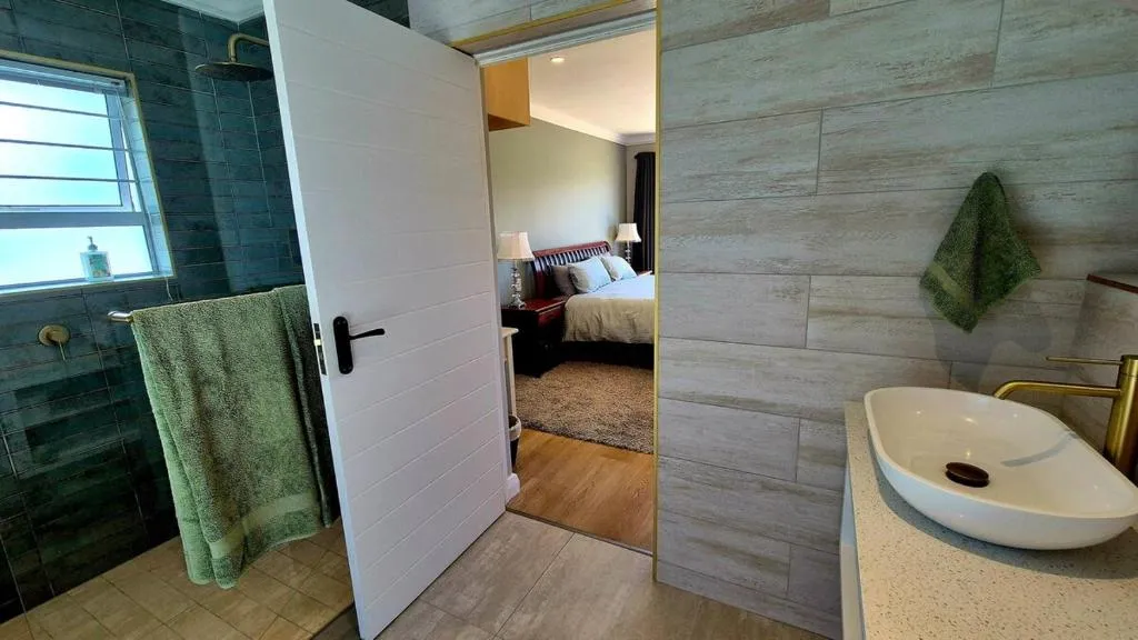 En-suite bathroom with a blue-tiled shower and a doorway through to the bedroom
