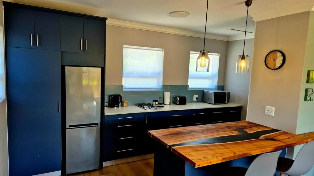 Kitchen with navy cabinetry, a stainless fridge and pendant lights over the counter