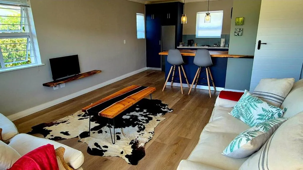Open living room with a cowhide rug, kitchen bar and TV on the far wall