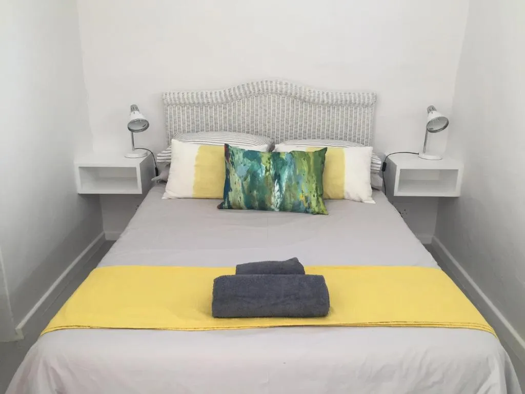 Made-up double bed with folded towels, cane headboard and floating nightstands