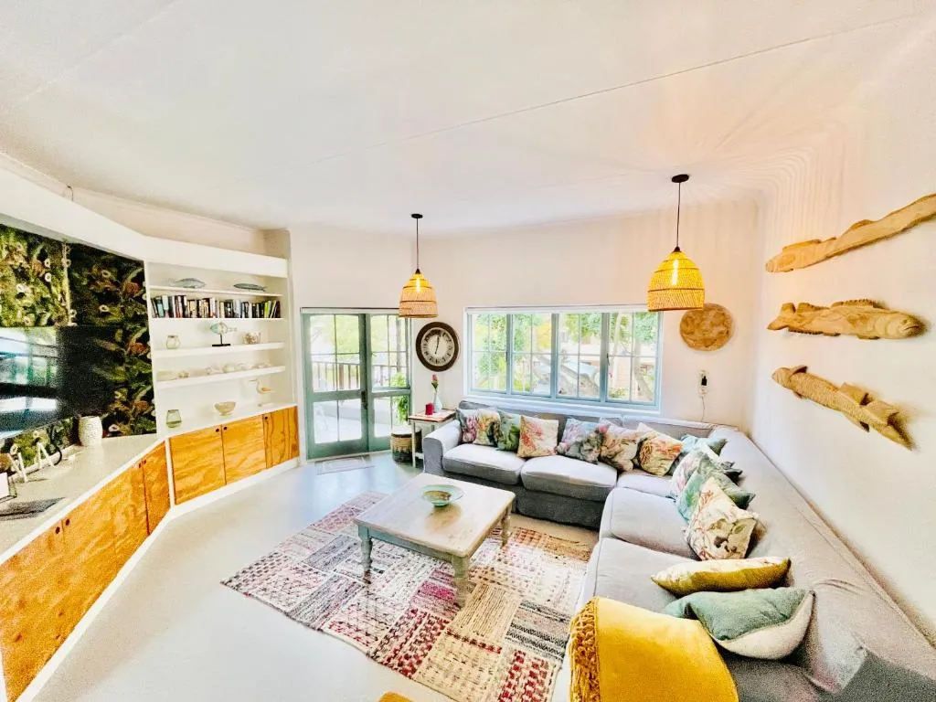 Curved open-plan lounge with a grey corner sofa, patterned rug and driftwood fish sculptures on the wall