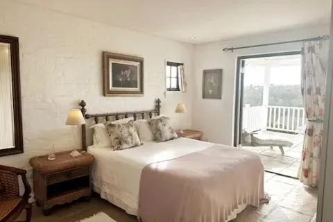 Bedroom with a wrought-iron bed frame, pink linens and French doors onto the terrace