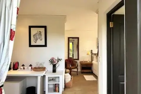 Hallway leading past a framed zebra print into a furnished guest bedroom