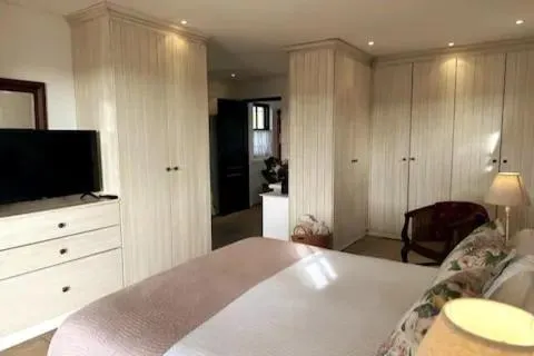 Second bedroom with built-in cream wardrobes, a TV and a floral bedspread