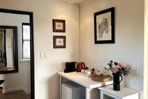 Corner tea and coffee station with a kettle, mugs and a mini fridge below