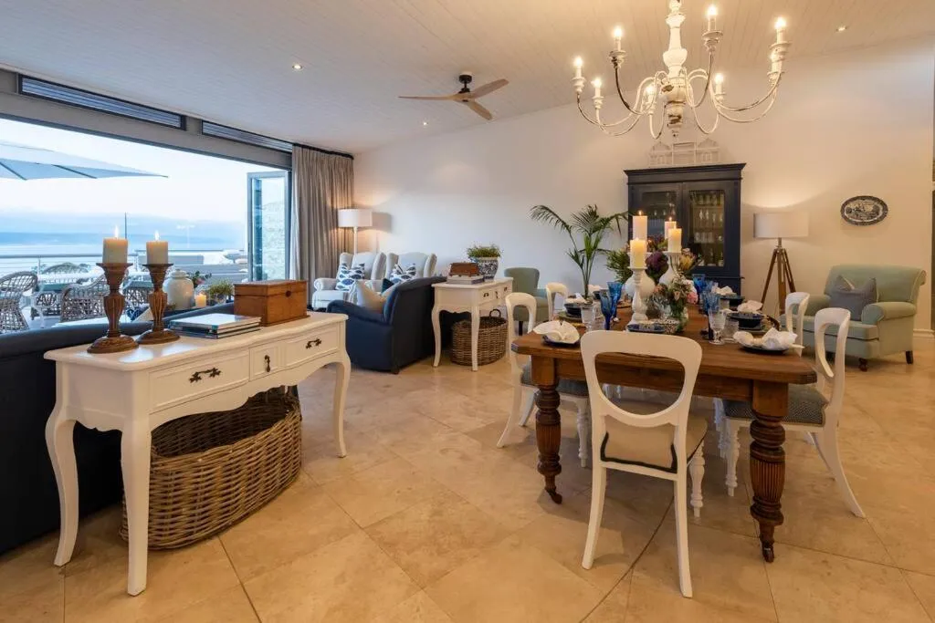 Dining and lounge area with a wrought-iron chandelier, ball-and-claw table and sea view through the window