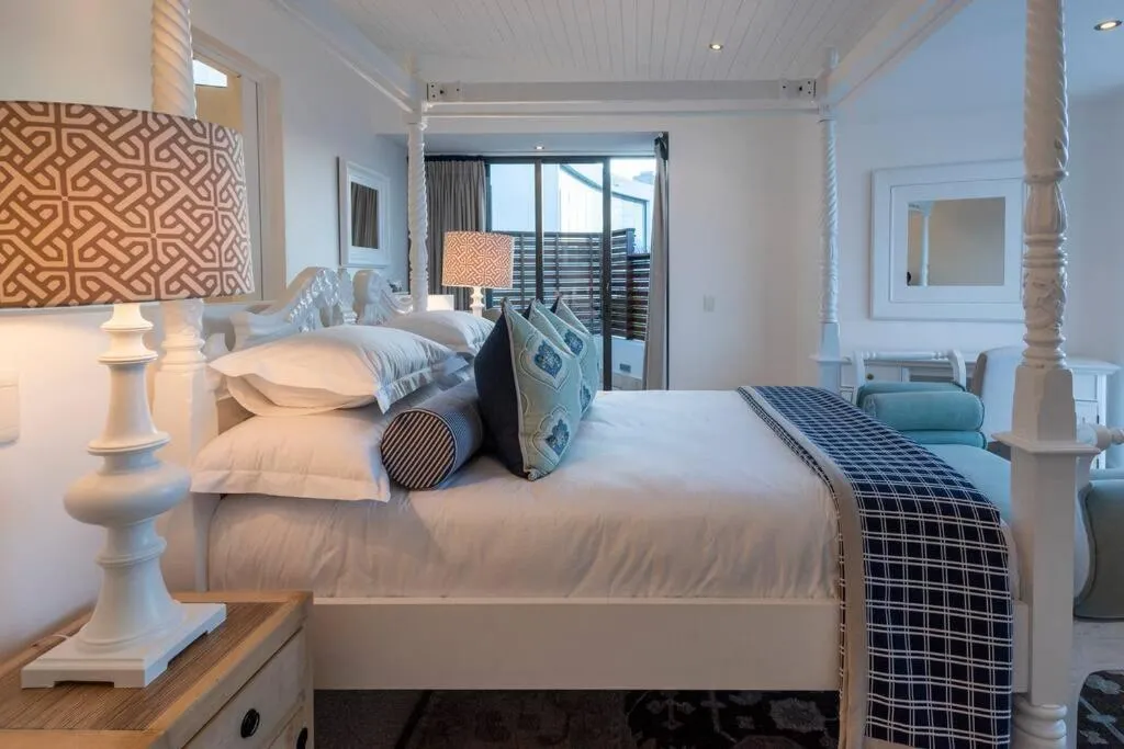 Same four-poster bedroom suite viewed from the foot of the bed toward the balcony door