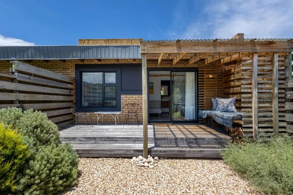 Brick and timber studio exterior with a covered deck, outdoor table and chairs
