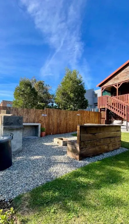 Gravel braai area with wooden fencing, firepit and the wooden house visible beyond