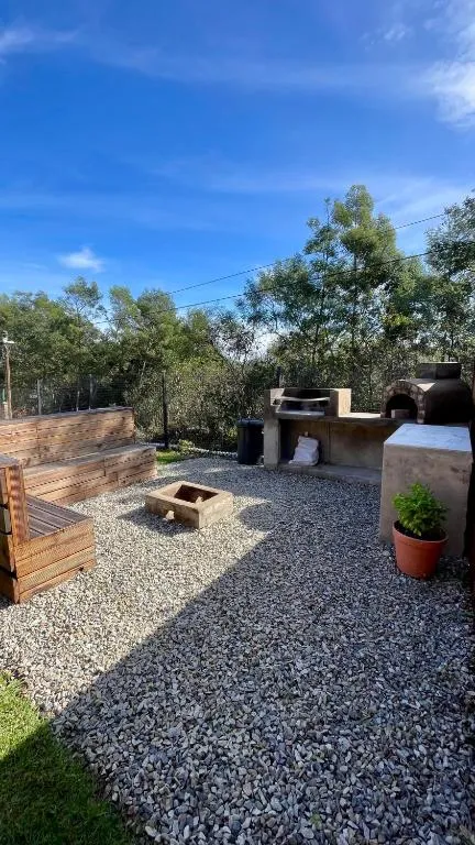 Braai station with fire pit, wooden bench seating and a potted plant on gravel