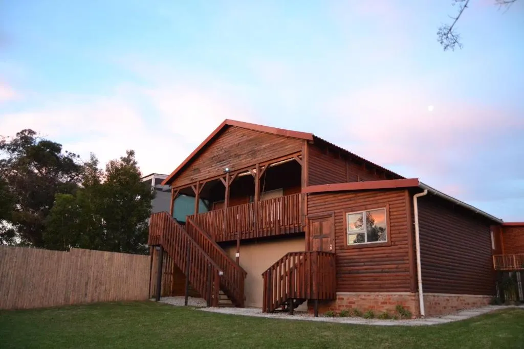 Two-storey wooden house exterior with covered balcony and timber staircase at dusk