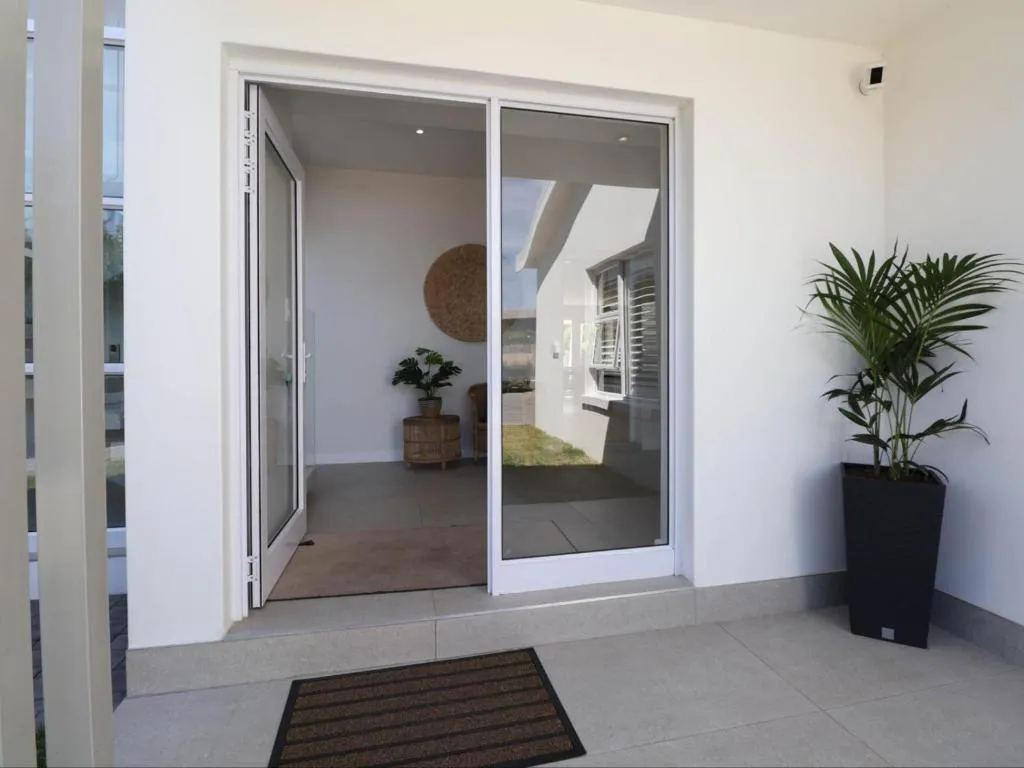 Glass entrance doors opening onto a paved patio with potted palms