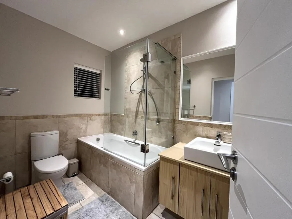 Bathroom with corner bath, walk-in glass shower, and vanity with basin