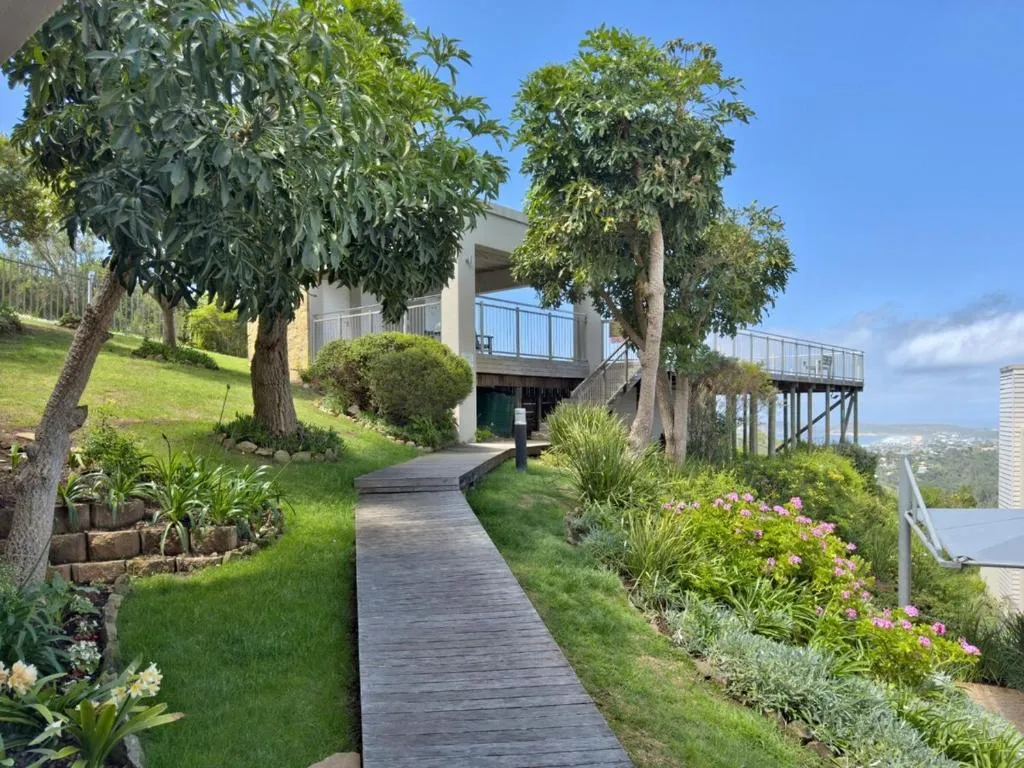Multi-level building exterior with timber walkway through a landscaped garden