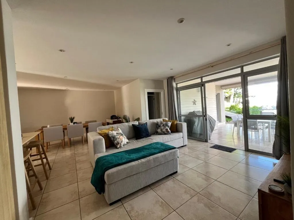 Open-plan living area with sofa, dining table, and breakfast bar seating