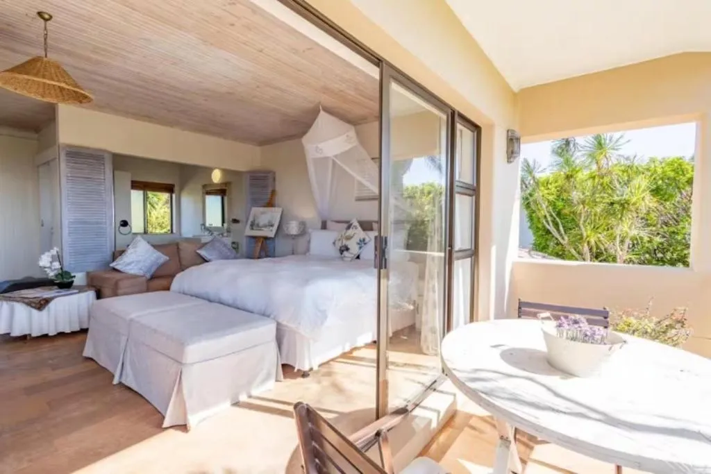 Bedroom balcony with a round table and chairs looking out over palm trees and greenery