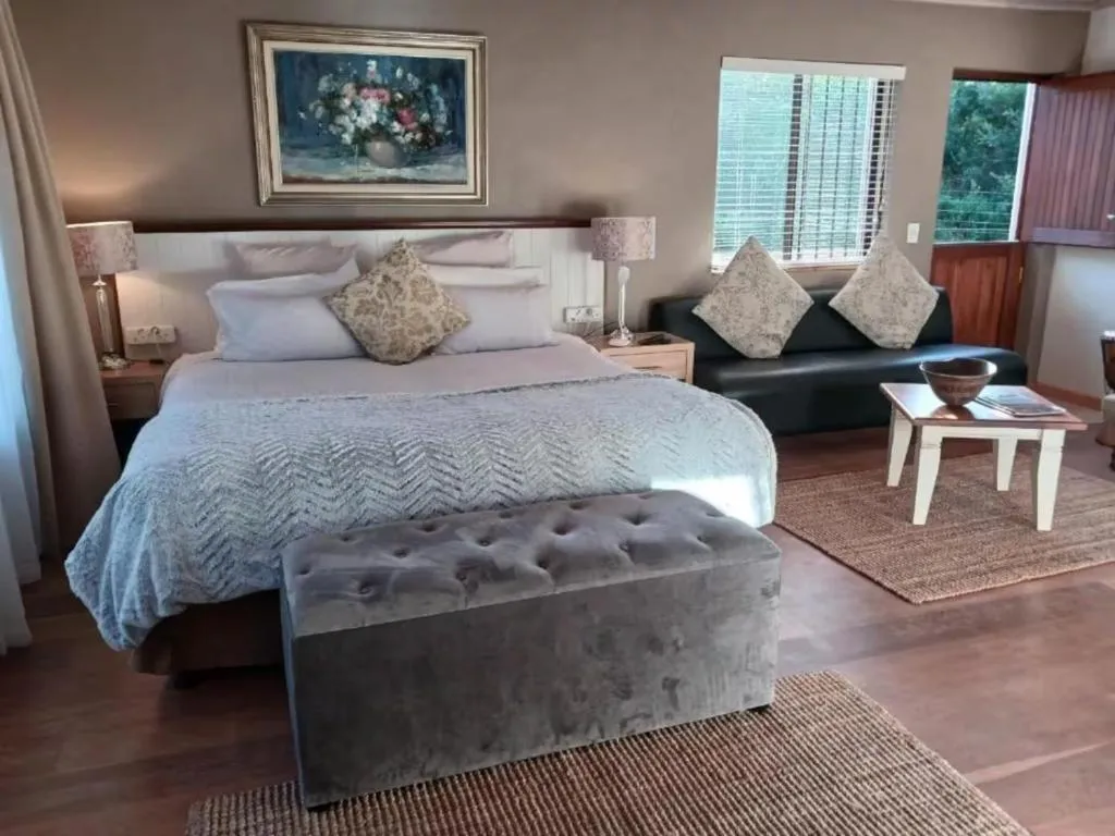 Bedroom with a tufted grey ottoman, navy couch and a floral still-life painting above the bed