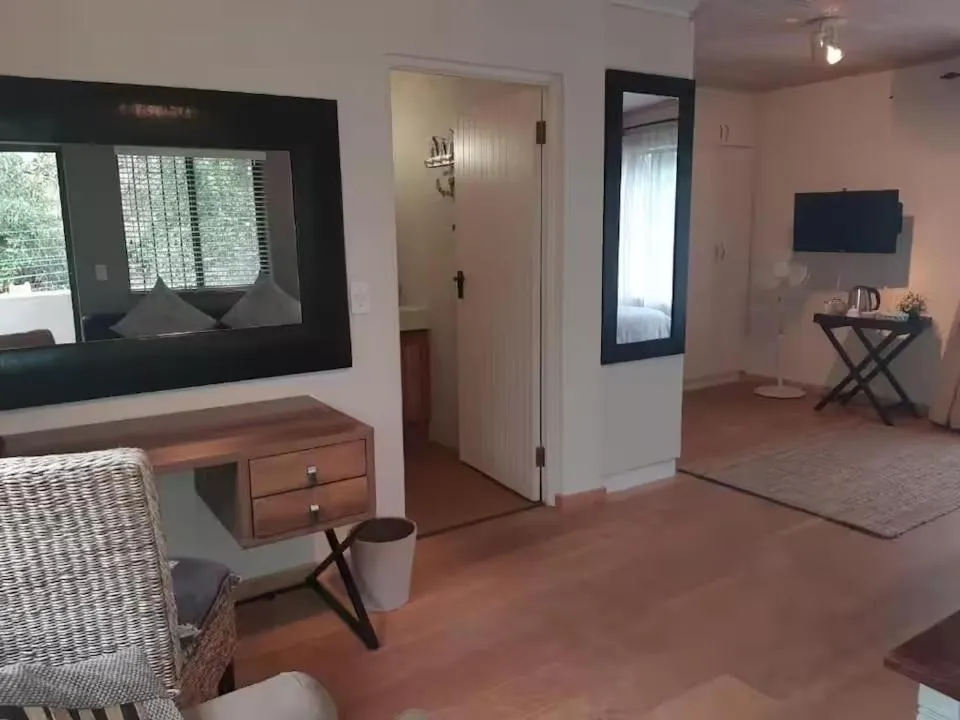 Hallway with a mirror, television and kettle station leading to an en-suite bathroom door