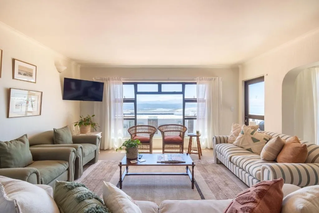 Living room with sofas, a wall-mounted TV and a picture window framing mountains and sea