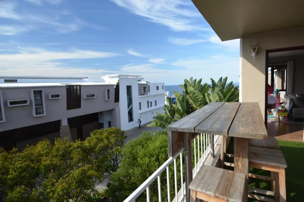 Timber balcony bar table looking past a neighbouring building to a strip of sea on the horizon