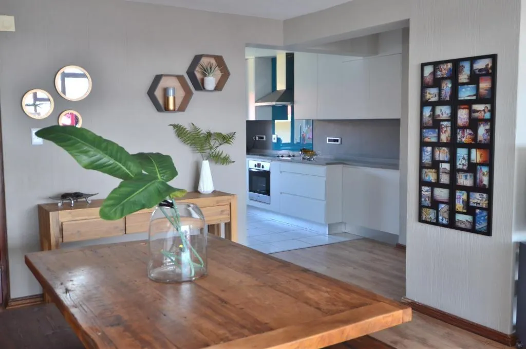 Dining table with a photo-collage wall and a view through to the open-plan kitchen