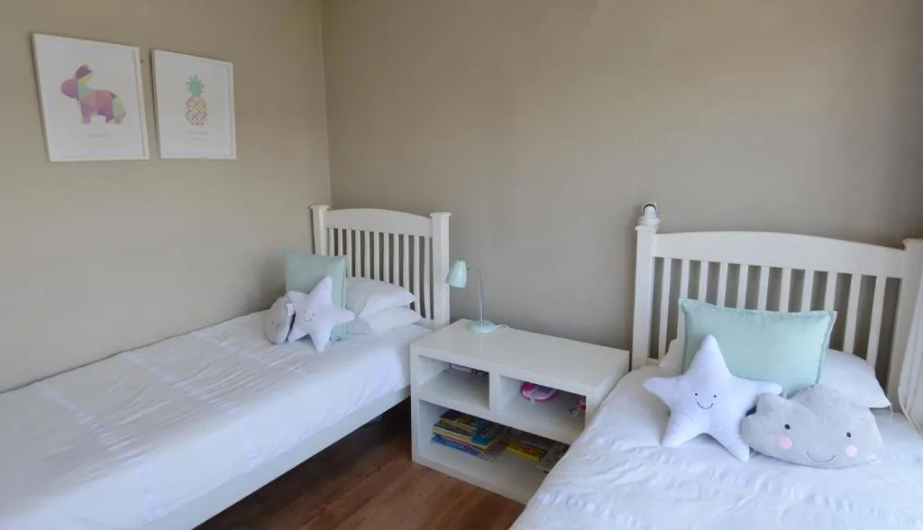 Twin kids' bedroom with star-shaped cushions, a storage cubby and framed animal prints