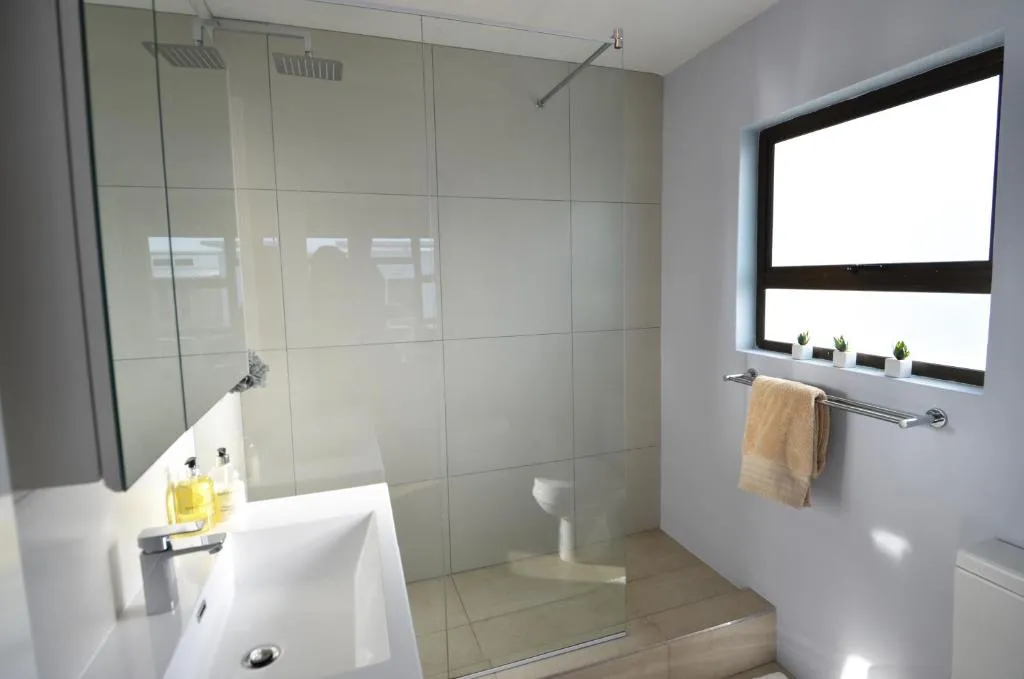 Walk-in shower with a full glass screen, rain head and a mirrored vanity unit