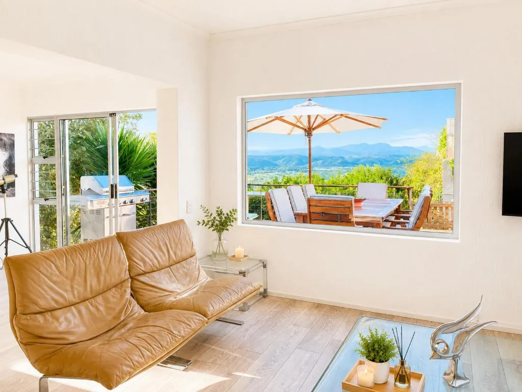 Living room with tan leather sofas and a picture window framing the terrace and mountain view