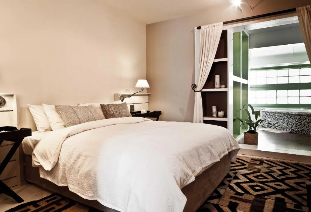 Bedroom with cream linen bedding and a glass door onto an ensuite bathroom