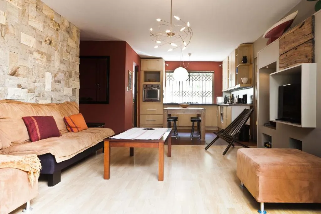 Living room with stone feature wall, tan sofa and built-in display shelving