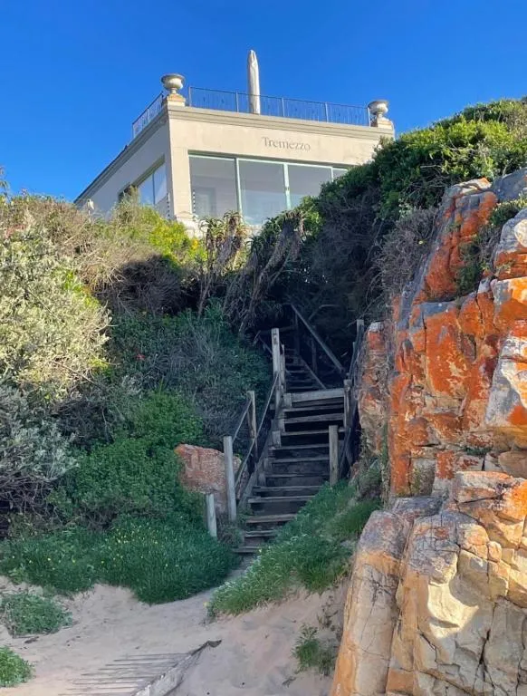 View from the beach path up wooden stairs to the villa's terrace, marked with the name Tremezzo