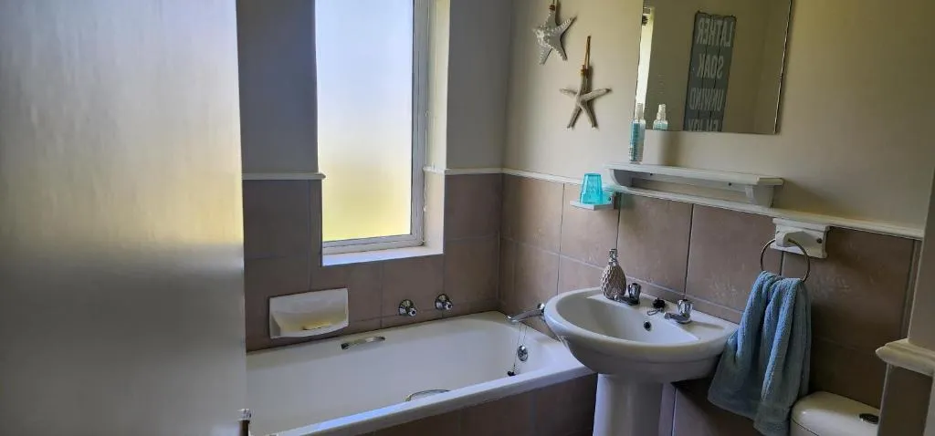 Bathroom with a built-in bathtub, pedestal basin and starfish wall decor