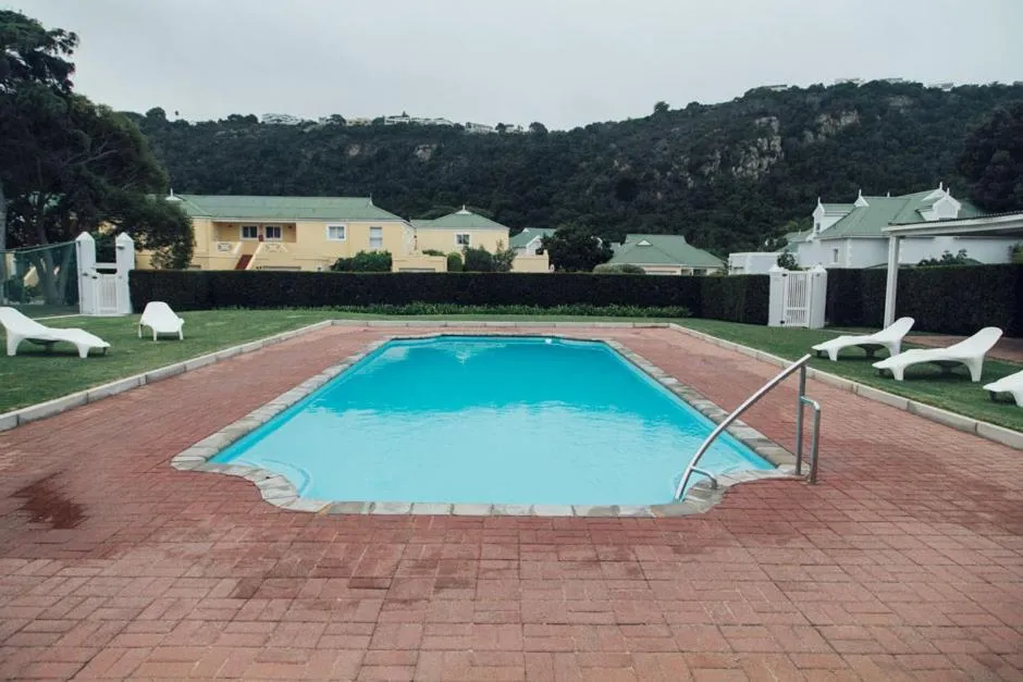 Communal swimming pool on the estate with sun loungers, lawn and hills behind
