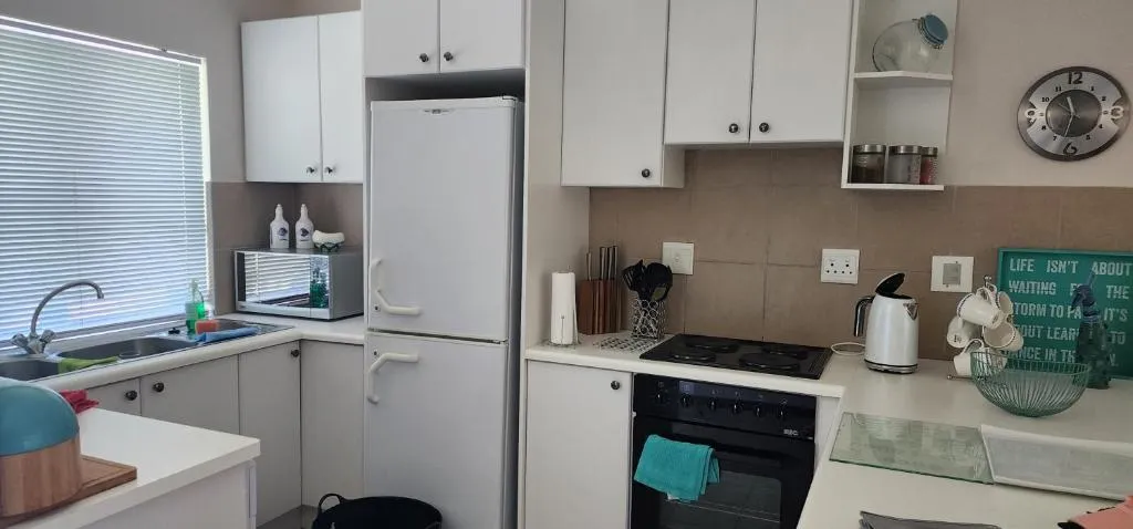 White fitted kitchen with a fridge-freezer, electric hob and oven under the counter