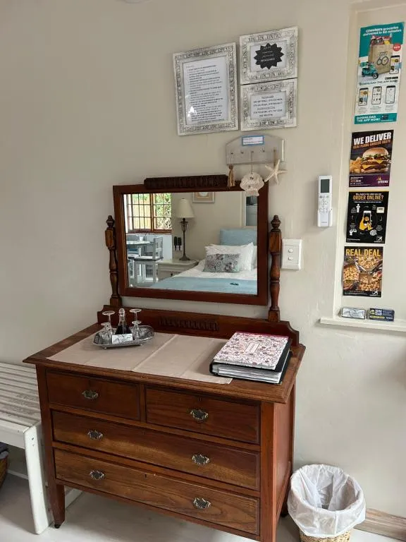 Antique wooden dresser with a tilting mirror reflecting the bed behind it