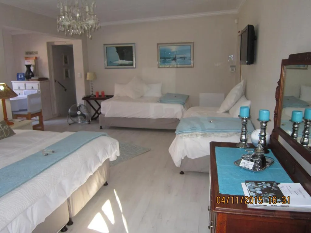 Wide view of the multi-bed guest room with chandelier, TV and seating area