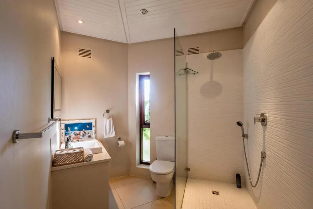 Bathroom with a walk-in glass shower, rain showerhead, and tiled walls