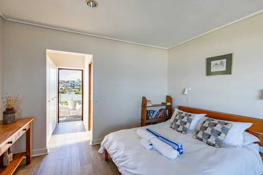 Bedroom with a doorway opening onto a balcony overlooking neighbouring rooftops
