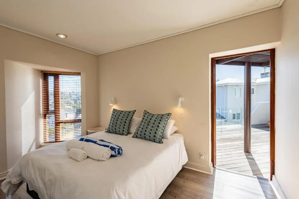 Bedroom with wood blinds and a door opening directly onto the rooftop deck