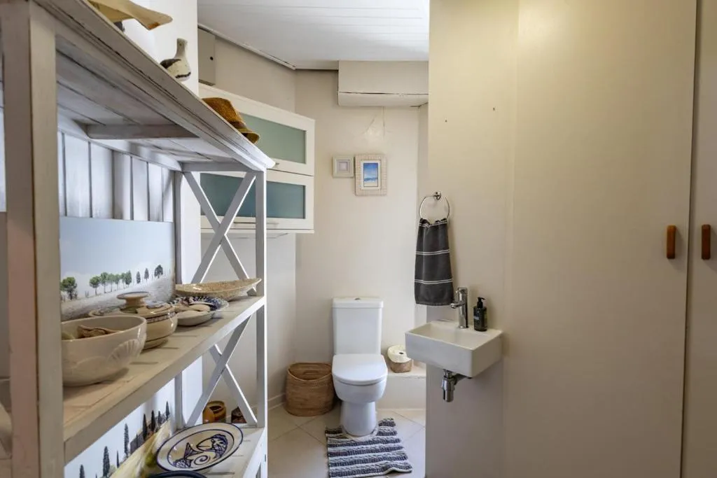 Small guest toilet with open shelving, decorative bowls, and a narrow window