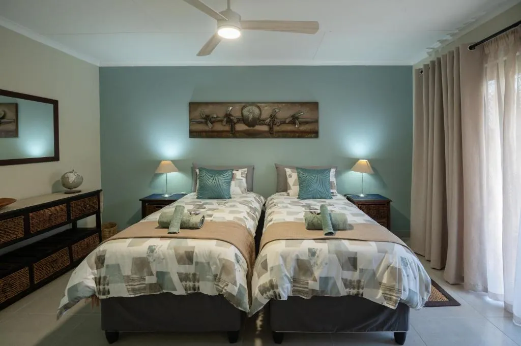 Double bedroom with a sage-green feature wall, carved wall art panel and bedside lamps