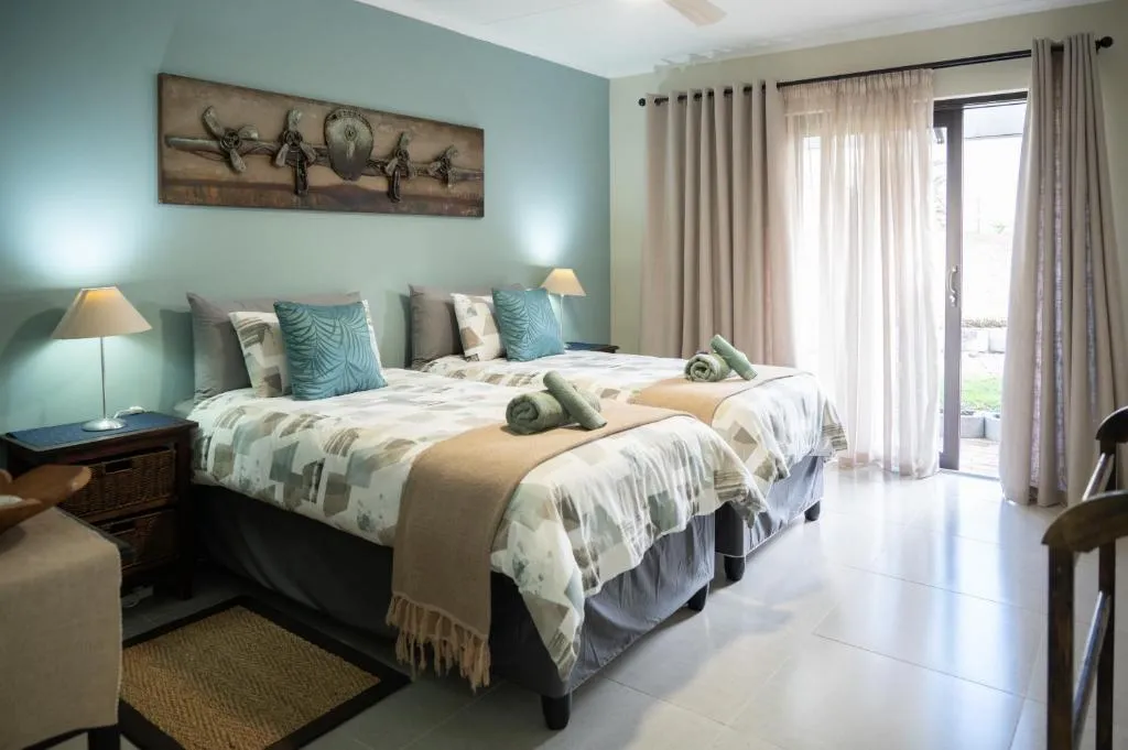 Twin bedroom in the same sage-green tone, matching lamps either side of two single beds