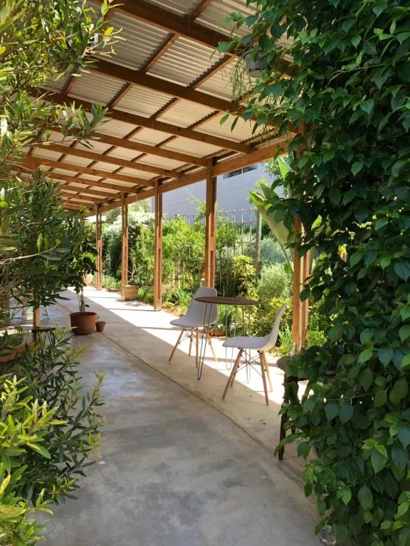 Covered timber pergola walkway with a bistro table and chairs set among lush garden greenery