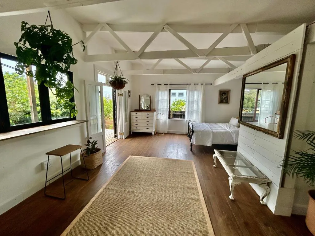 Main bedroom with white-painted beam ceiling, antique dresser and doors onto a balcony