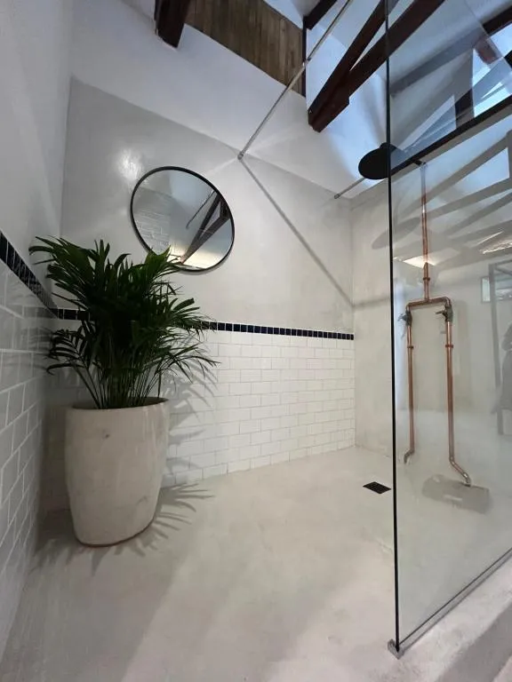 Open-plan shower with a glass partition, exposed copper pipework and white subway tile