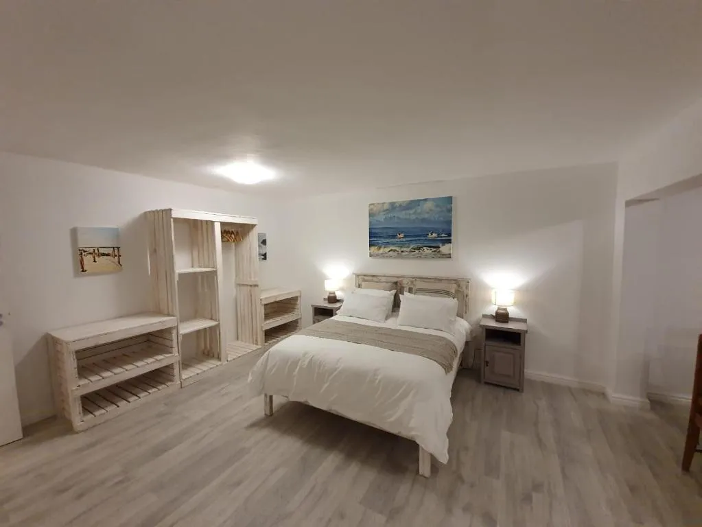 Open bedroom with pallet-style wardrobe shelving and light wood-look flooring